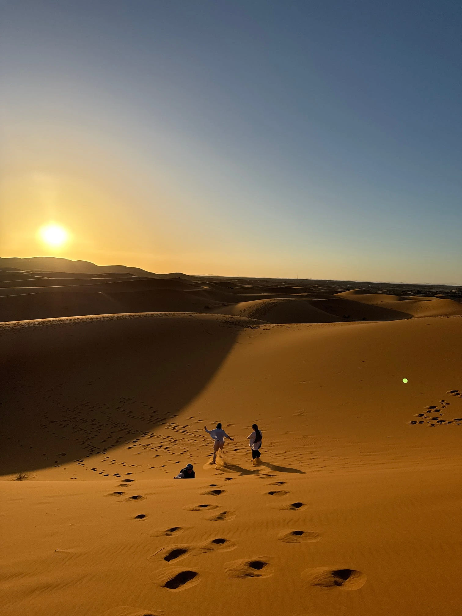 Sunset casting golden and orange light over the sand dunes of the Merzouga Sahara Desert in Morocco